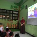 Ava teaching by a projector in the front of class in Indonesia