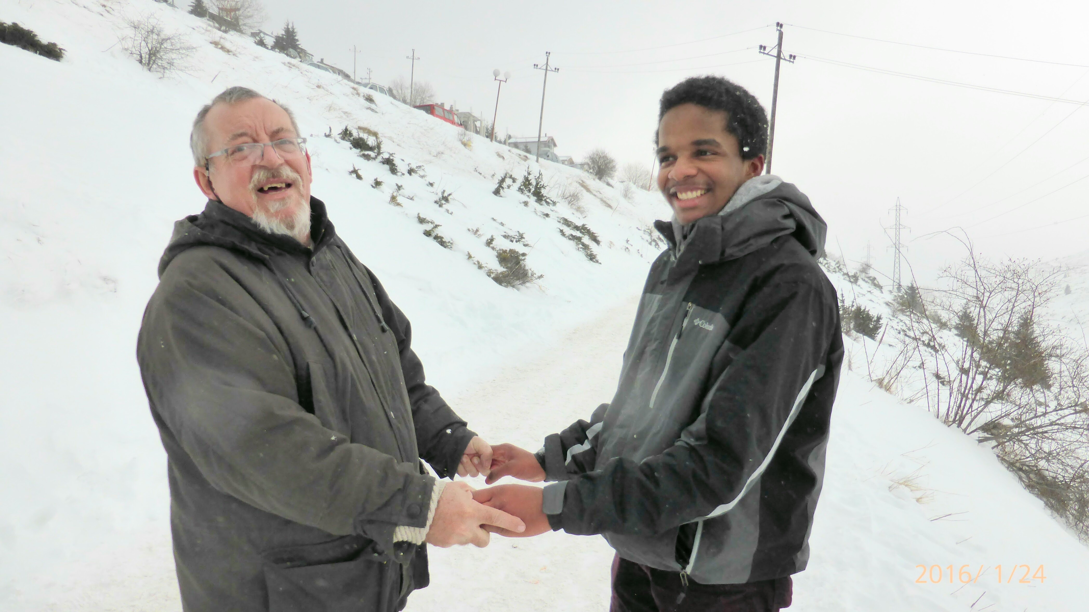 Maxwell holding hands with his host father smiling in the snow