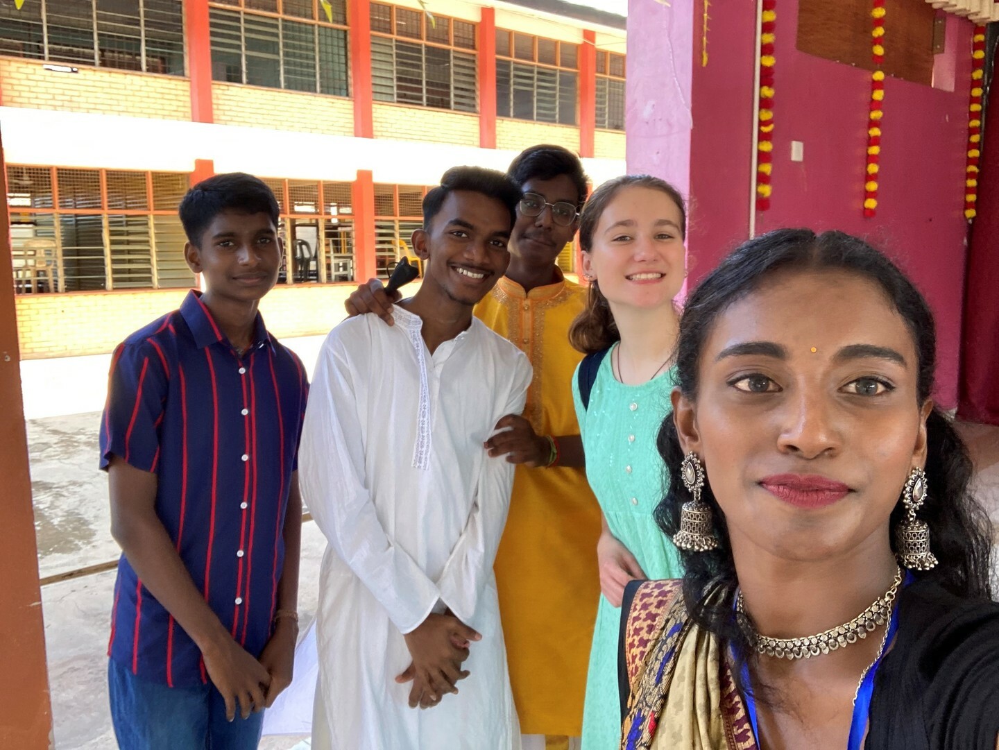 Josephina poses smiling with classmates outside of a school building