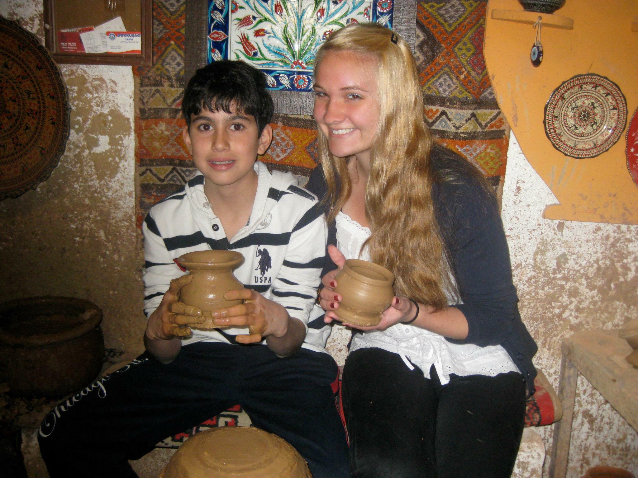 Kendra smiling and posing with her host brother and ceramic pots they made in pottery class