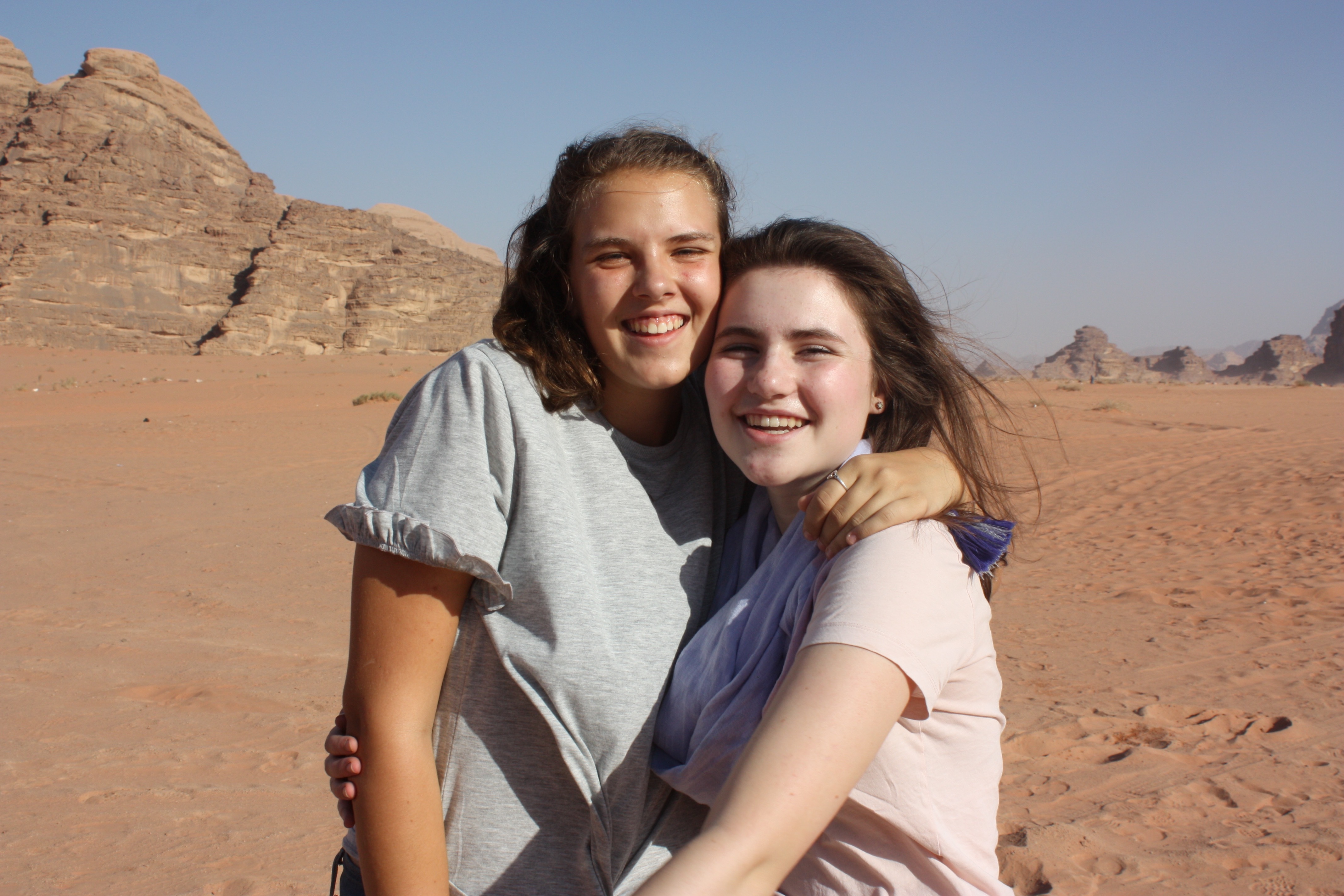Phoebe and a friend hugging and smiling in the desert