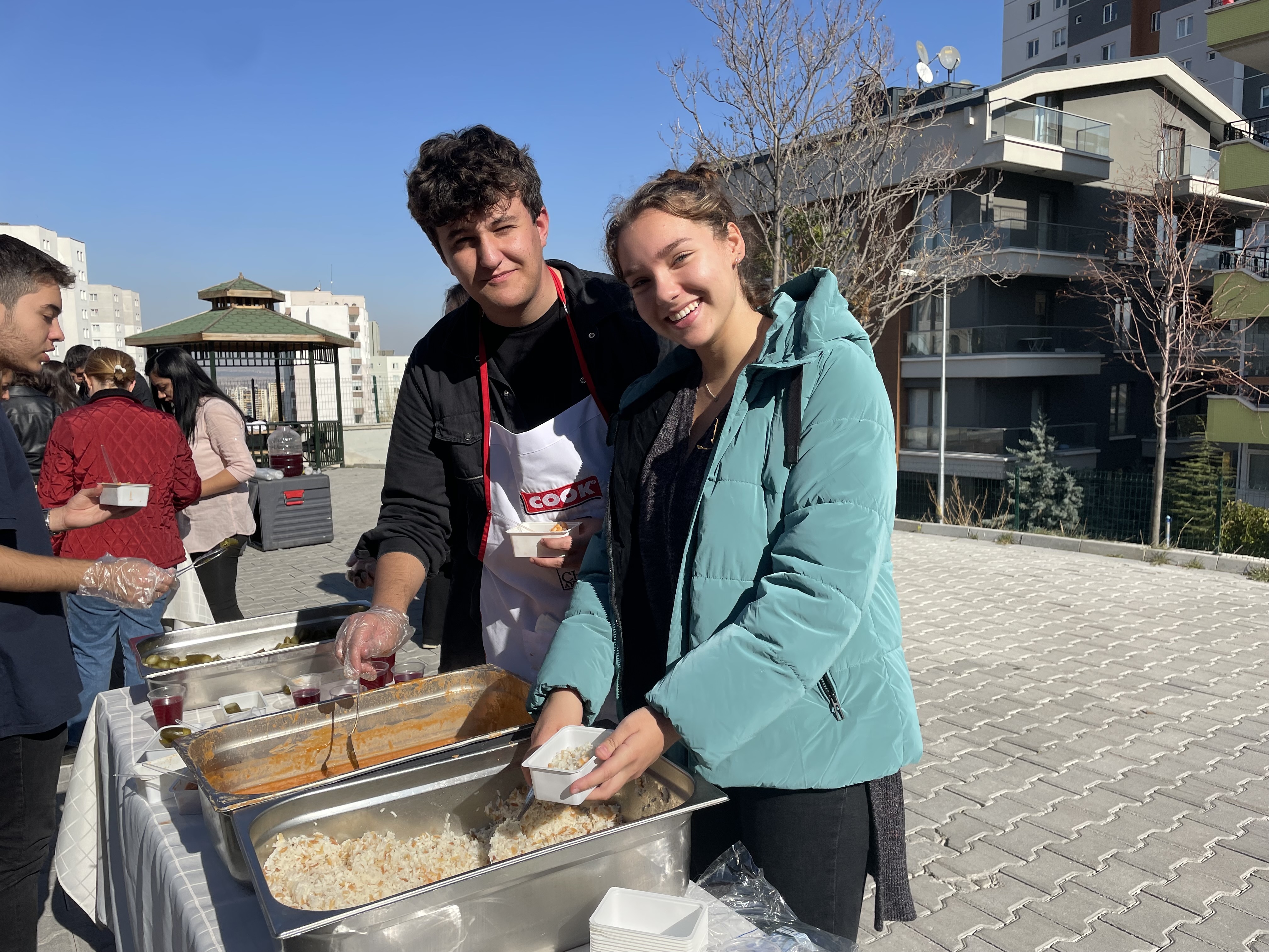 Martine outside serving food, smiling with another club member