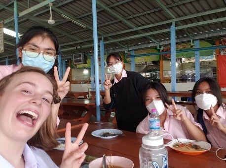 Josie smiling with three classmates all giving the peace sign
