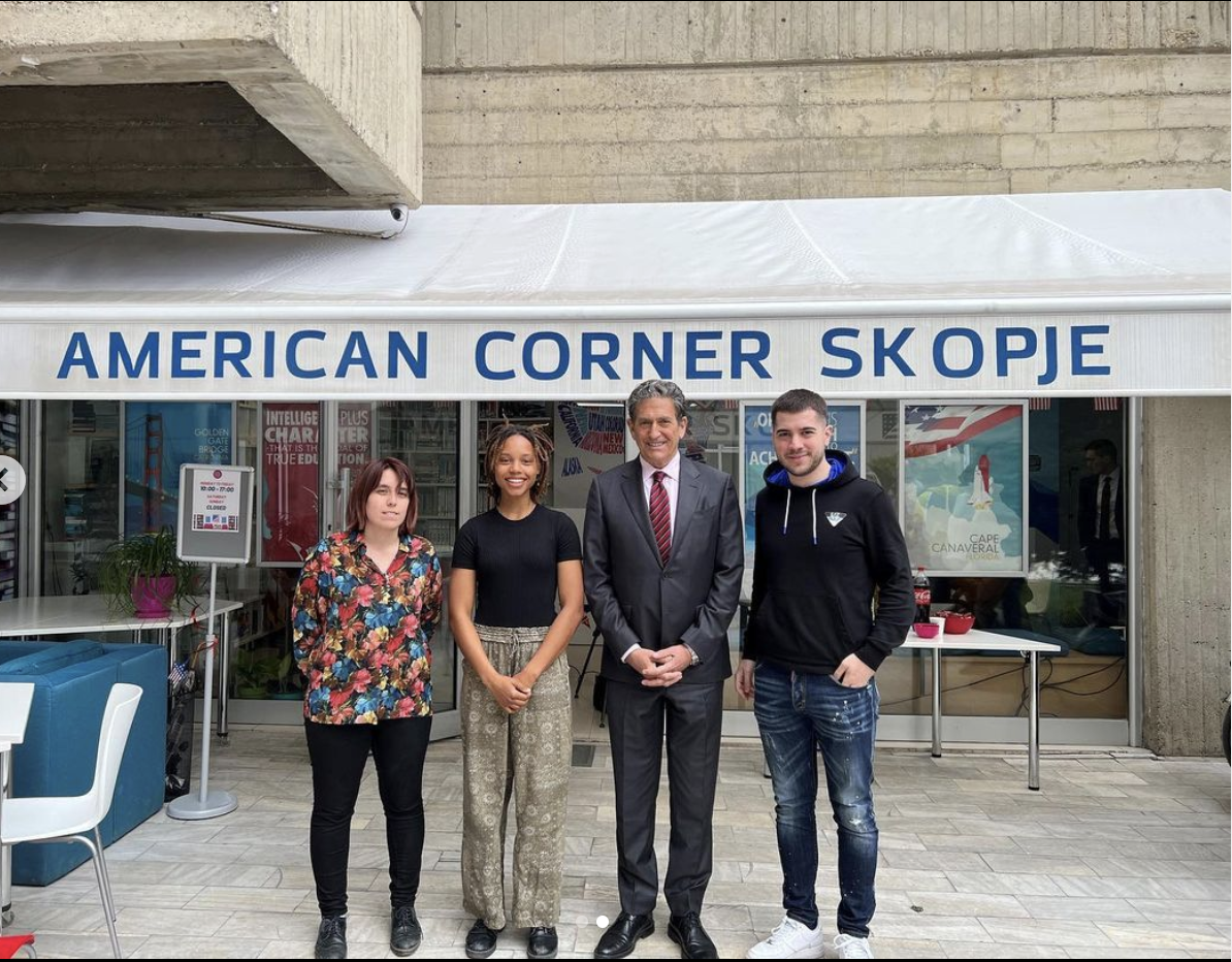 Four people smiling in front of a store front