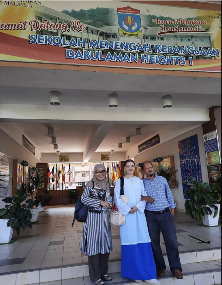 Isabel in her school uniform smiling with her host parents