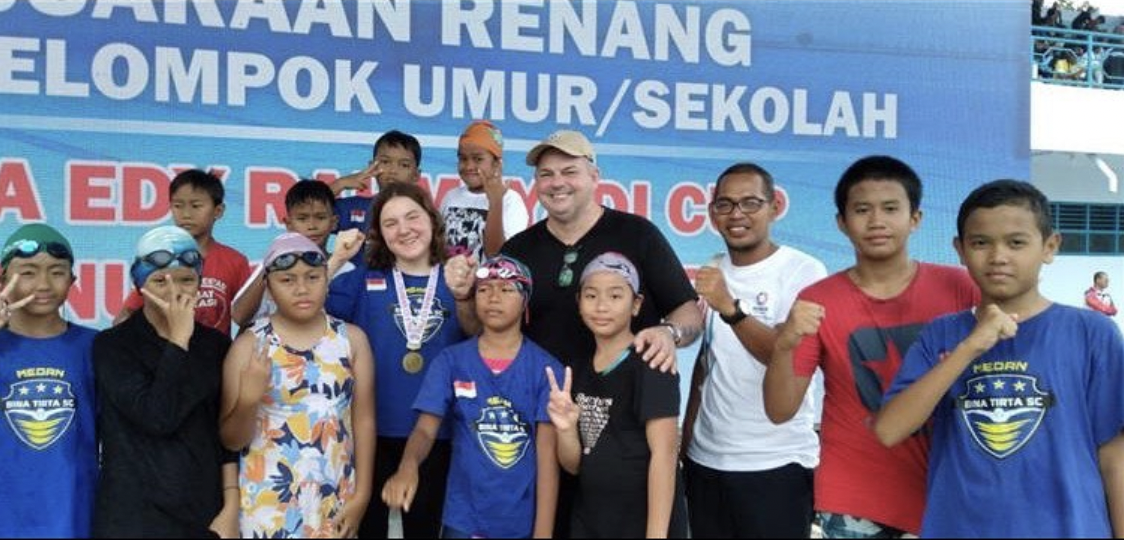 Mary in a group photo of swimmers wearing her medals
