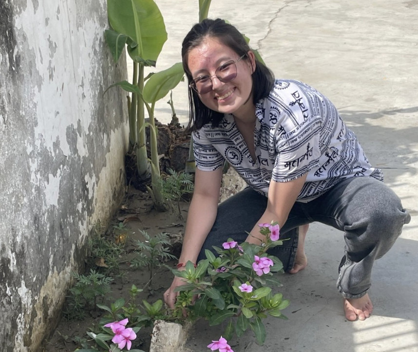 Alisa planting flowers at her host father's childhood temple