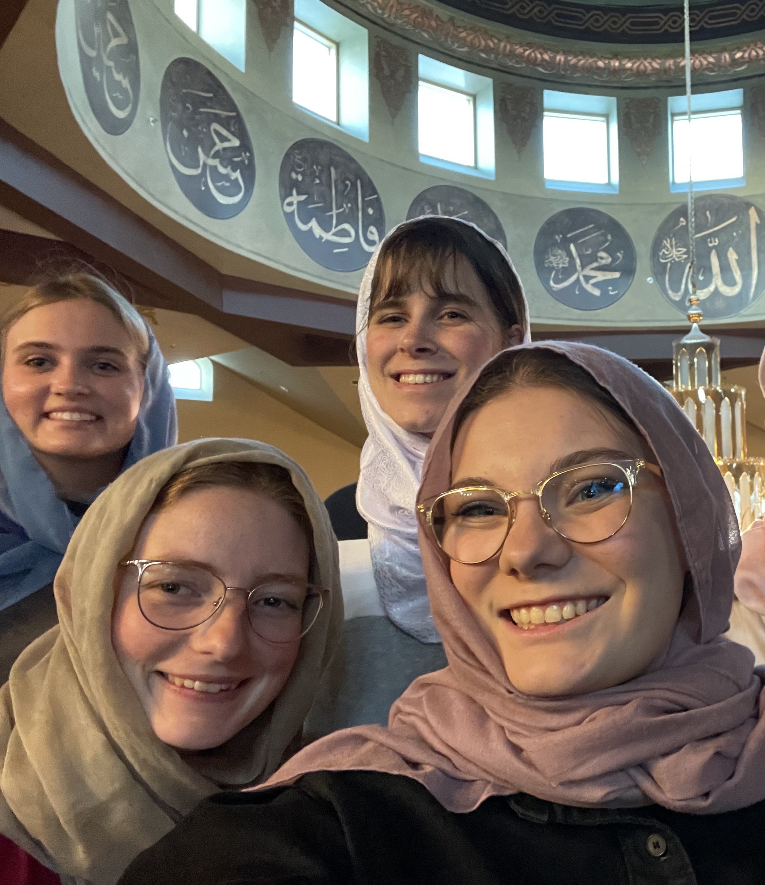 Eden smiling in a selfie with three other friends inside of a mosque