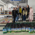 Chloe and a group of student standing in front of donation boxes for Eid.