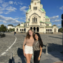 Two young women standing in front of a historical looking building 