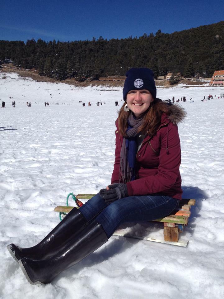 Sophia smiling while sitting on a sled in the snow