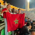 Morocco students in a soccer stadium posing with the Moroccan flag